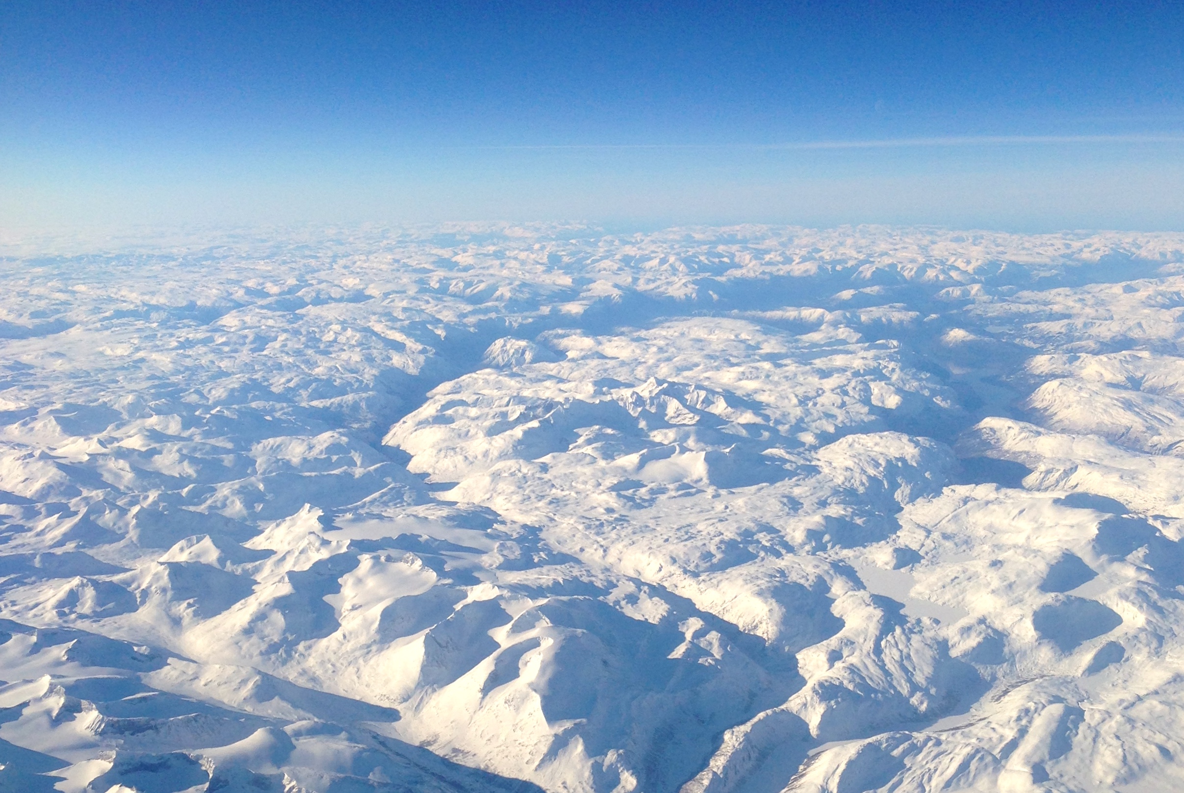 Hurrungane sett fra luften. Toppene skiller seg ut som alpine tinder midt i bildet.