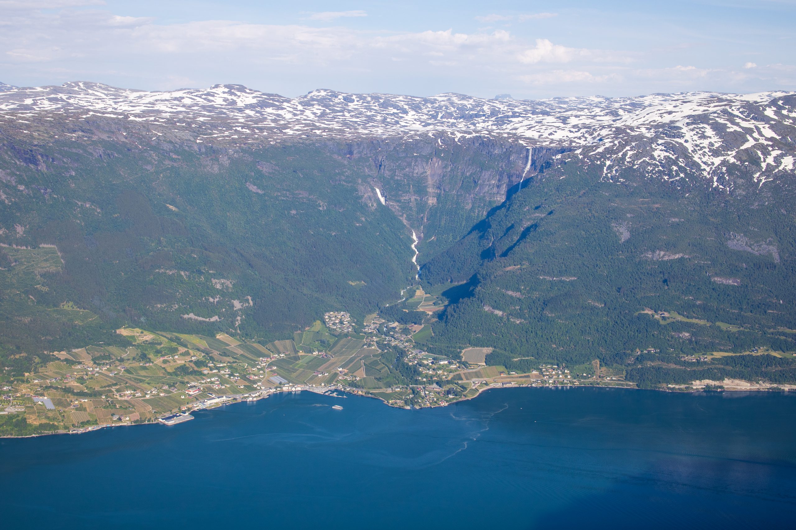 Lofthus i Sørfjorden sett fra Vardanuten. Fra Hardangervidda platået renner noen spektakulære fossefall; Bjørnabykset og Skrikjo.