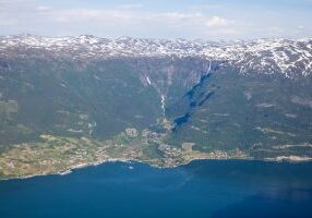 Lofthus i Sørfjorden sett fra Vardanuten. Fra Hardangervidda platået renner noen spektakulære fossefall; Bjørnabykset og Skrikjo.