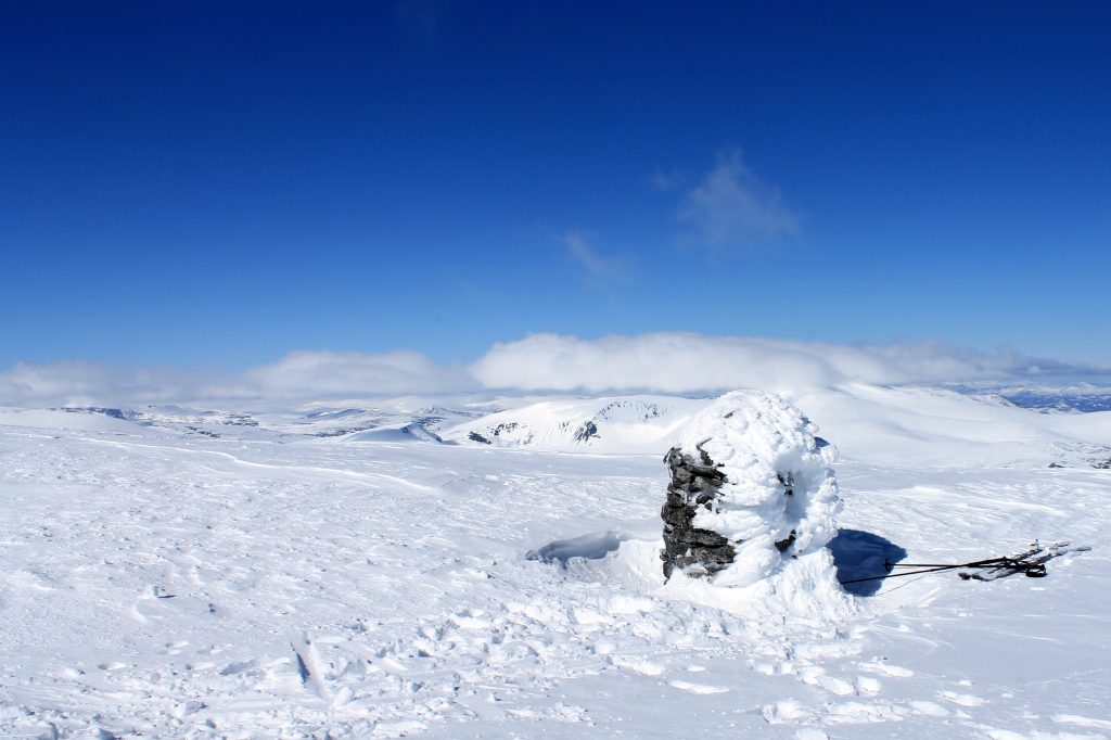 Toppvarden på Besshøe 2.258 moh, med en skudekket Glittertind i bakgrunnen.